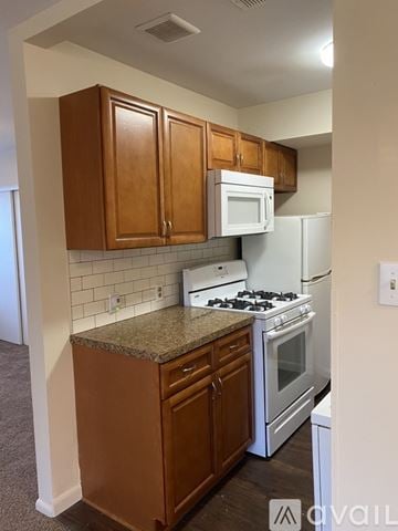 Philadelphia apartment for rent - A kitchen with brown cabinets and white appliances.