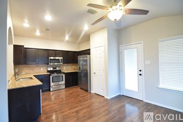 Temple house for rent - A kitchen with black cabinets and a white stove top oven.
