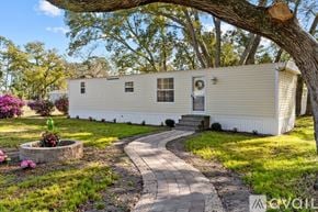 Ocean Isle Beach house for rent - A mobile home is surrounded by a well-kept lawn and a variety of trees.