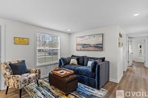 Ocean Isle Beach house for rent - A living room with a blue couch, a chair, and a rug.