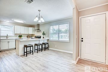 Hinesville house for rent - A kitchen with white cabinets and a bar area.