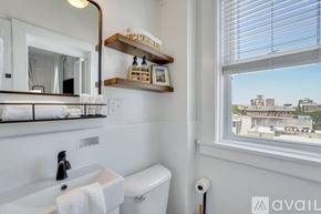 Savannah apartment for rent - A bathroom with a white sink, toilet, and a window with a view of buildings outside.