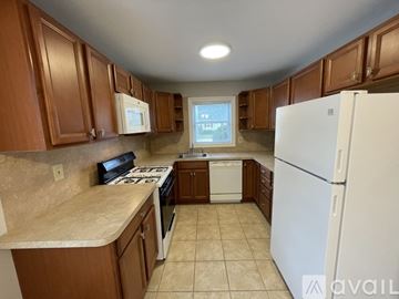 Brick Township apartment for rent - A kitchen with brown cabinets and a white refrigerator.