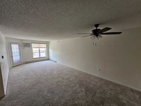 Owatonna apartment for rent - A room with a ceiling fan and carpeted floor.