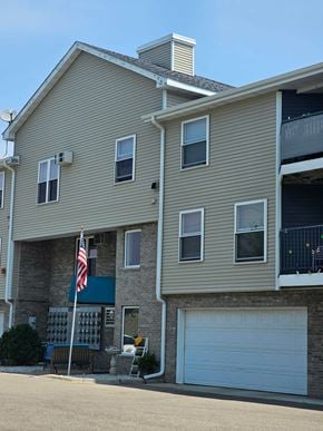 Owatonna apartment for rent - A two-story building with a garage door and an American flag.