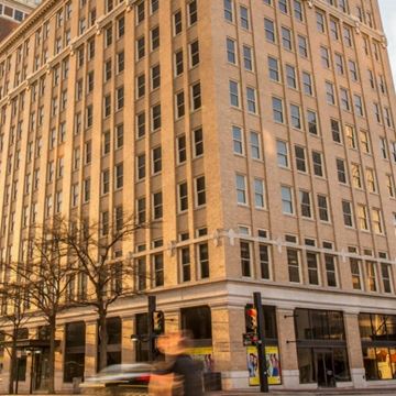 Tulsa apartment for rent - A tall building with many windows is in the foreground.