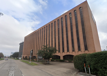 Houston apartment for rent - A large red building with many windows is situated on a street.