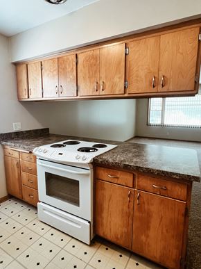 Lincoln apartment for rent - an empty kitchen with wooden cabinets and a white stove