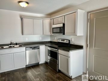 Box Elder apartment for rent - A kitchen with white cabinets and a black countertop.
