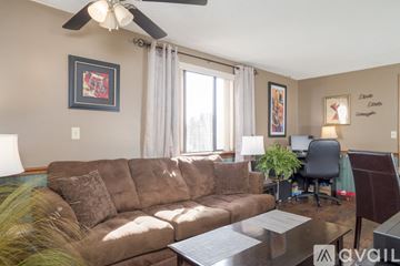 Lockport apartment for rent - A living room with a brown couch and a ceiling fan.