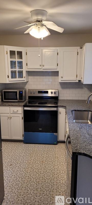 Greensboro house for rent - A kitchen with white cabinets and a black stove top oven.