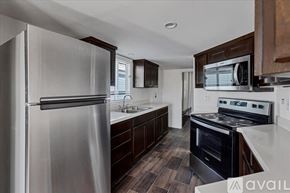Barstow apartment for rent - A modern kitchen with a stainless steel refrigerator and dark wood cabinets.