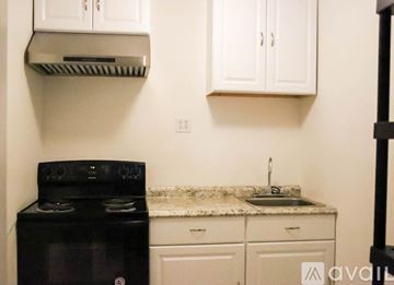 Cartersville house for rent - A kitchen with a black stove and white cabinets.