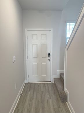 Pensacola townhouse for rent - A white door with a black handle is in the middle of a hallway with a grey carpet.