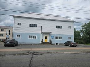 Stellarton apartment for rent - A large white building with a yellow door and a blue sign on the front.