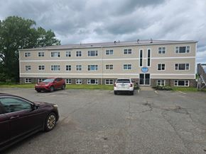 Stellarton apartment for rent - A building with a blue sign on the front and cars parked in front.