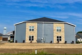 Belgium apartment for rent - A large, modern building with a grey exterior and a black roof.