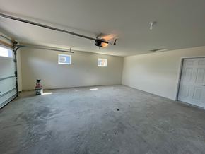 Belgium apartment for rent - A spacious garage with a concrete floor and white walls.