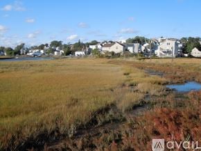 Revere house for rent - A grassy field with a small stream running through it and houses in the background.
