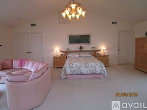 Revere house for rent - A bedroom with a large bed and a pink chair.