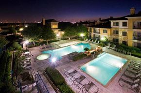 Austin apartment for rent - A swimming pool surrounded by chairs and trees at night.