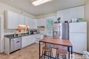 Charlottesville house for rent - A kitchen with white cabinets and a wooden table.
