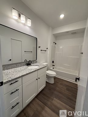 Madison apartment for rent - A white toilet sits in a bathroom next to a white sink and a white rug.