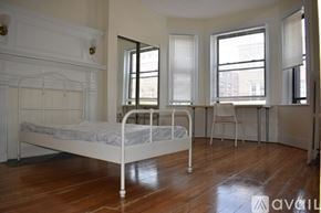 Boston apartment for rent - A white metal bed frame in a room with wooden floors and white walls.