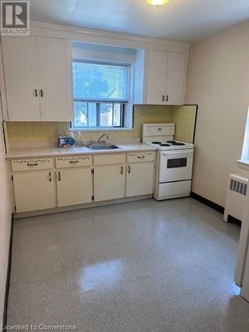 Hamilton apartment for rent - A small kitchen with white cabinets and a window.