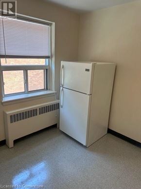 Hamilton apartment for rent - A white refrigerator in a room with a window and a radiator.