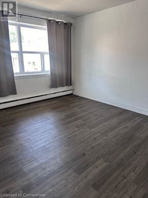 Dundas apartment for rent - A room with wooden flooring and a window with curtains.