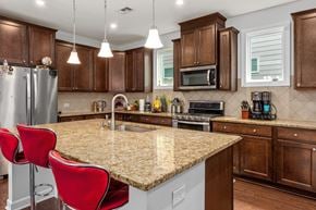 Apex house for rent - A kitchen with brown cabinets and a granite countertop.