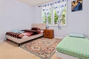 Apex house for rent - A bedroom with a large bed and a smaller bed in the corner.