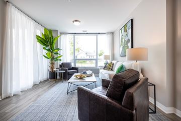Whitby apartment for rent - A living room with a brown leather couch and a large window with white curtains.