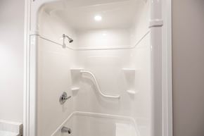 Whitby apartment for rent - A white shower stall with a door and a shower head.