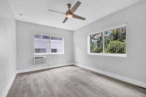 Bay Harbor apartment for rent - A room with a ceiling fan and a window showing a view of trees.