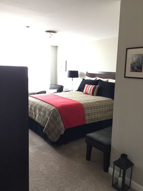 Oshawa apartment for rent - A bedroom with a bed, nightstand, and lamp.