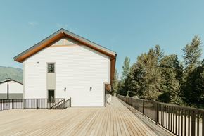 Revelstoke apartment for rent - A white building with a brown roof and a wooden deck in front.