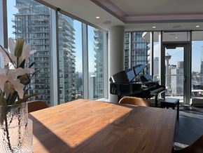 Calgary apartment for rent - A room with a wooden table and a piano in front of a large window with a city view.