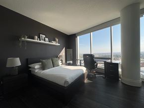 Calgary apartment for rent - A bedroom with a large bed and a view of the city.