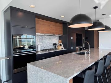 Calgary apartment for rent - A modern kitchen with dark cabinets and a marble countertop.
