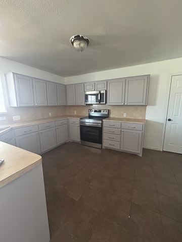 Killeen house for rent - A kitchen with white cabinets and brown flooring.