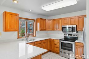 Coralville house for rent - A kitchen with white countertops and wooden cabinets.