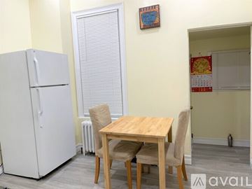 Jersey City house for rent - A kitchen with a white fridge, a table with chairs and a calendar on the wall.
