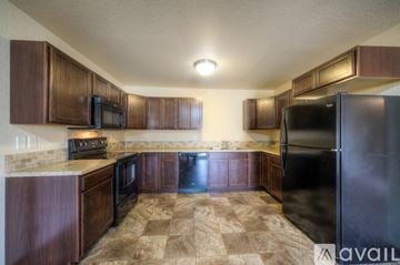 Rapid City apartment for rent - A kitchen with brown cabinets and a black refrigerator.