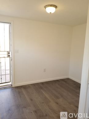 Pueblo house for rent - A room with wooden flooring and a window with a view of a balcony.