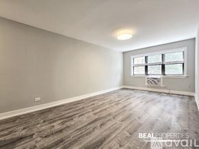 Chicago apartment for rent - A spacious room with wooden flooring and a window with blinds.