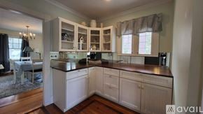 Ogunquit house for rent - A kitchen with white cabinets and a black countertop.