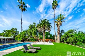 Los Angeles house for rent - A pool surrounded by palm trees and lawn chairs.