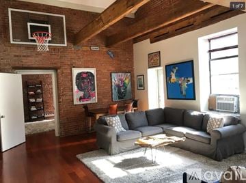 Norwalk apartment for rent - A living room with a grey couch and a basketball hoop on the wall.